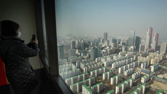 한 시민이 도심 아파트 밀집 지역을 촬영하고 있다. <연합뉴스>